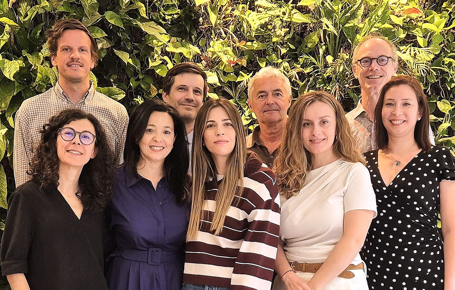 Group photo of OSE team in front of vertical garden wall, staff portrait.